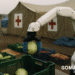 A SOMARICS soft robotic arm operates inside a modular relief station set up in a disaster-stricken area. The robot is gently sorting food supplies under a portable canopy, while local volunteers coordinate distribution. Dusty, damaged buildings are visible in the background, emphasizing the resilience and adaptability of the robotic system.